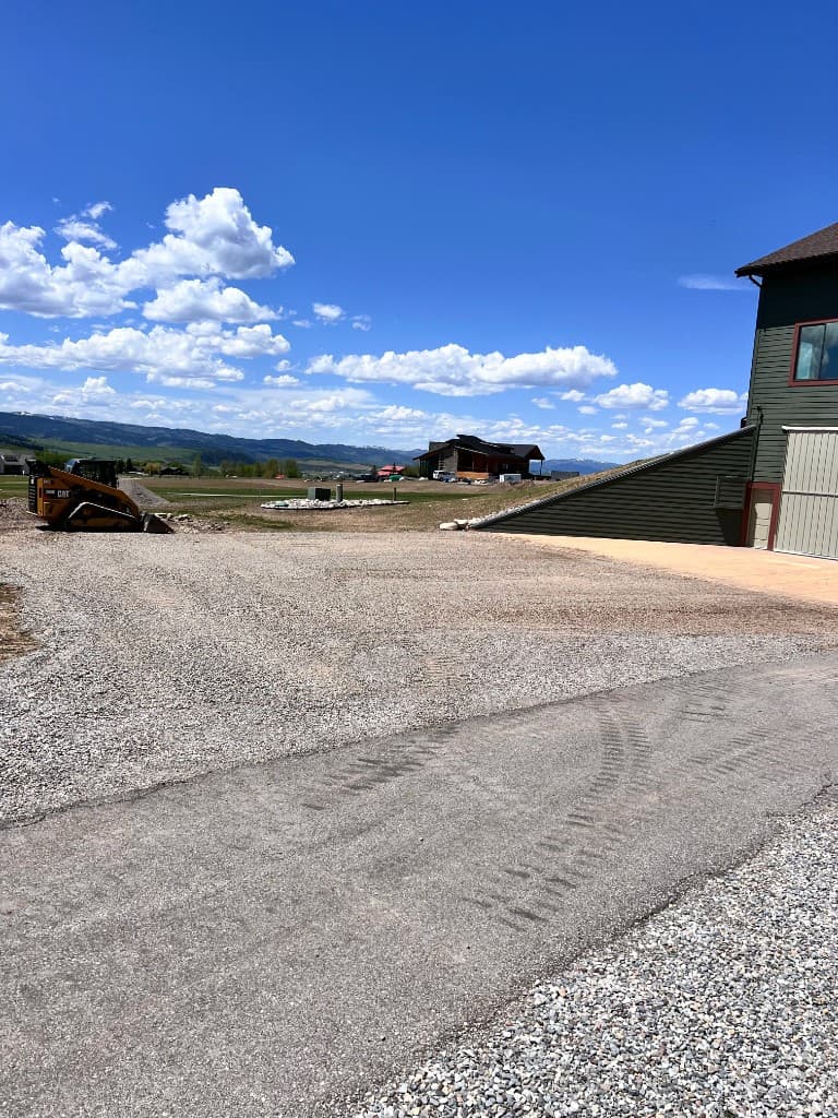 Gravel driveway installation with skid steer on site